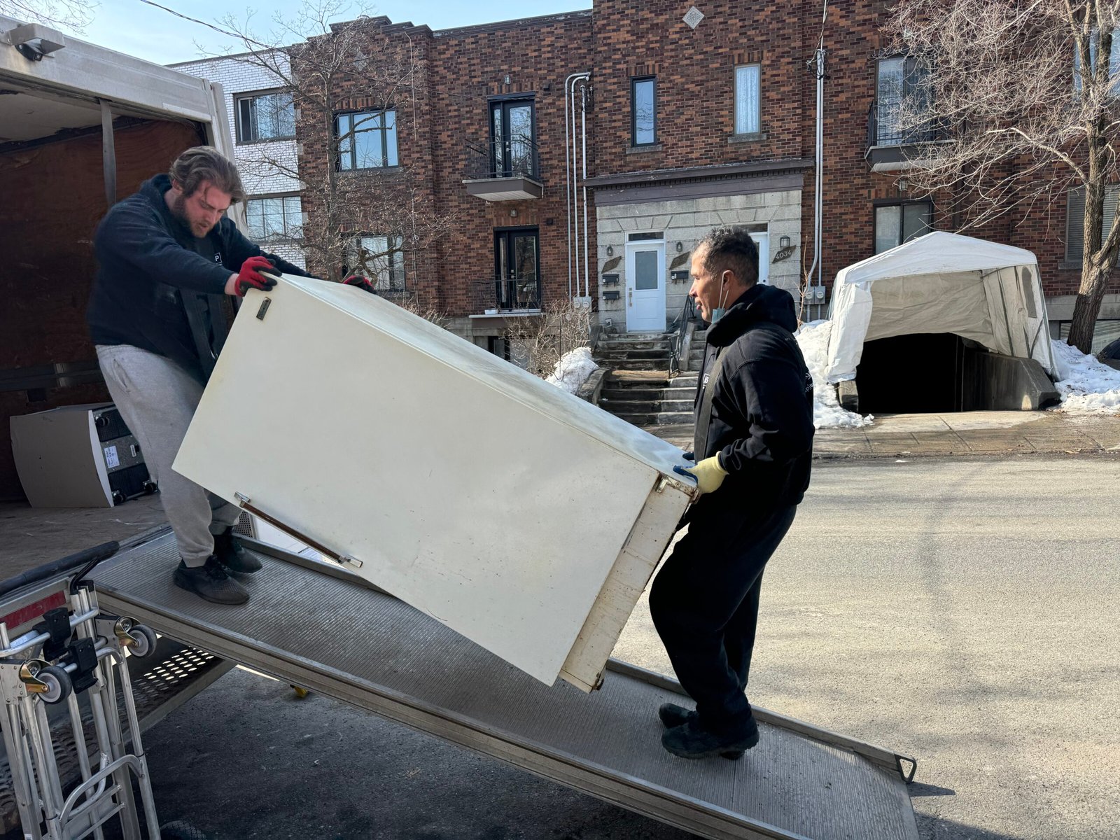 ASAP crew sliding an old refrigerator up the truck ramp
