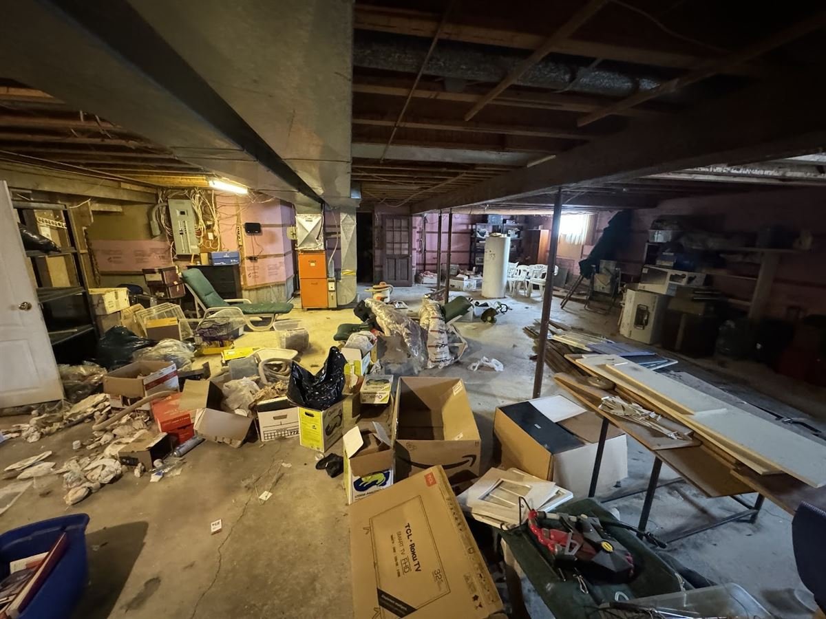 Cluttered unfinished basement full of boxes and old items before a cleanout
