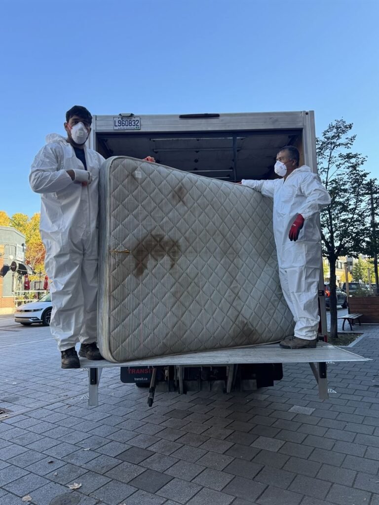 ASAP crew in protective suits loading a mattress onto the truck lift