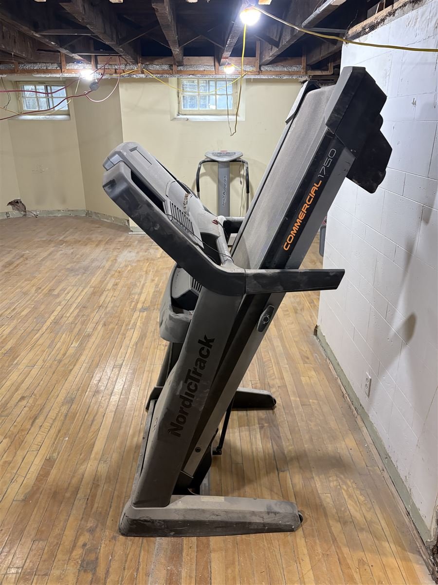 Old treadmill in a basement waiting for removal