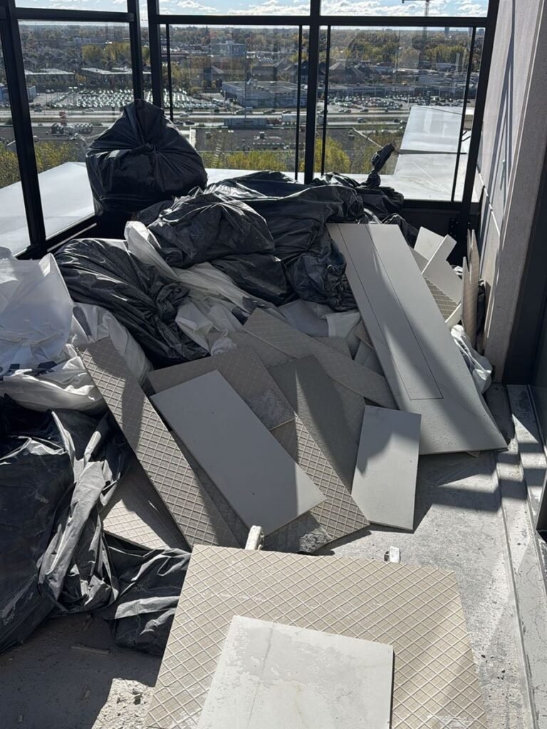 Bags and broken tiles from a flood cleanup piled on a balcony