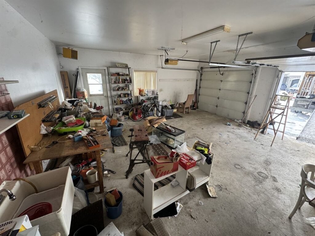 Cluttered double garage with tools, bikes and boxes before a cleanout