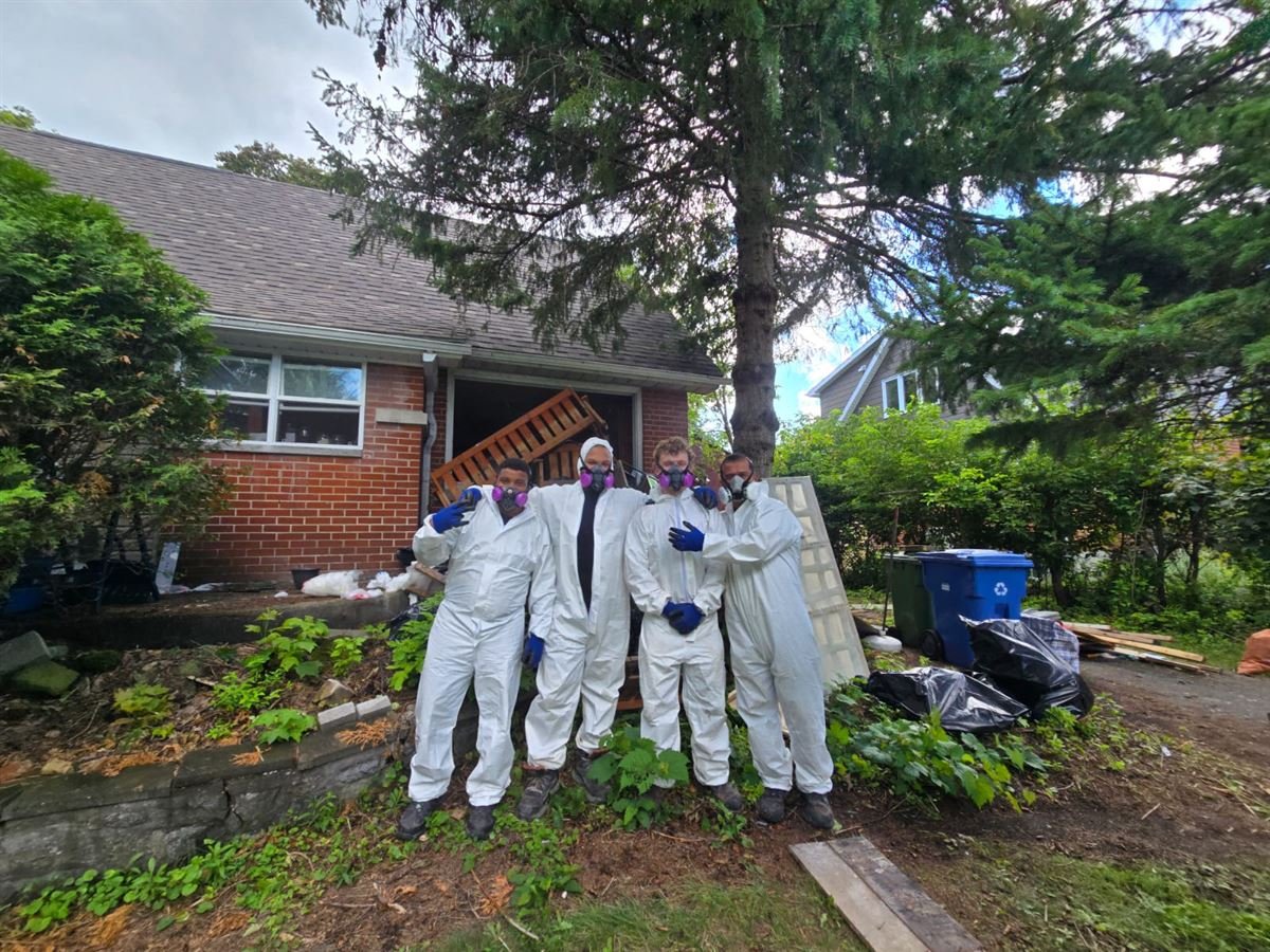 ASAP crew in protective suits and respirators outside a home cleanup job