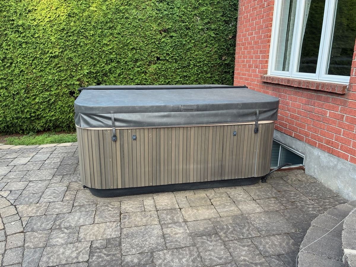 Covered hot tub on a stone patio before removal