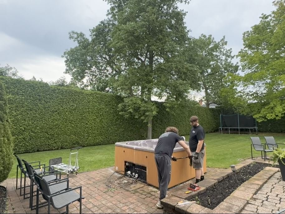 ASAP crew disconnecting and taking apart a hot tub in a backyard