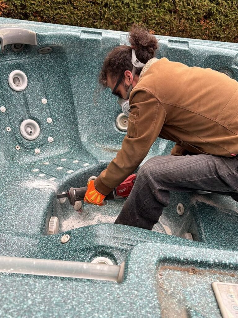 Crew member cutting a hot tub shell into pieces for removal