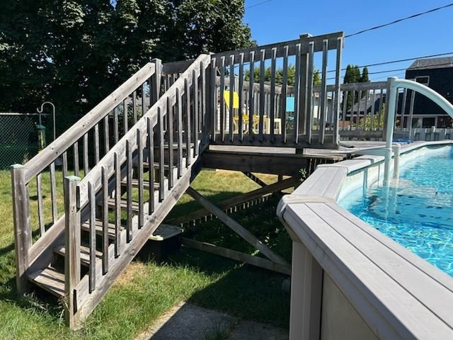 Above-ground pool with a wooden deck and stairs before removal