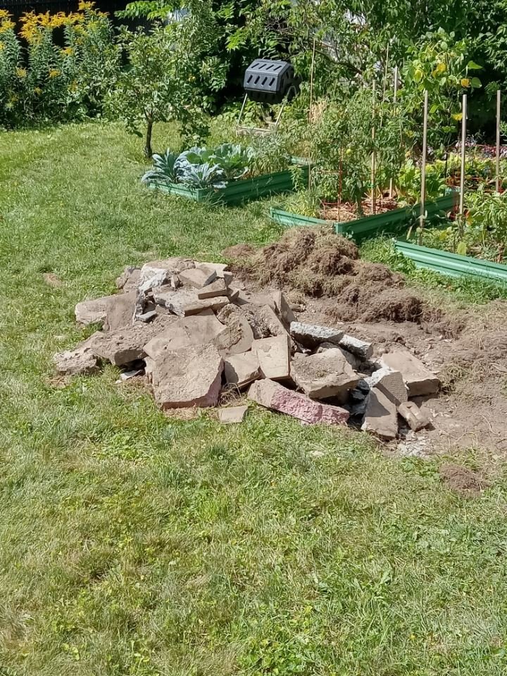 Leftover patio stones piled on the lawn where an above-ground pool stood