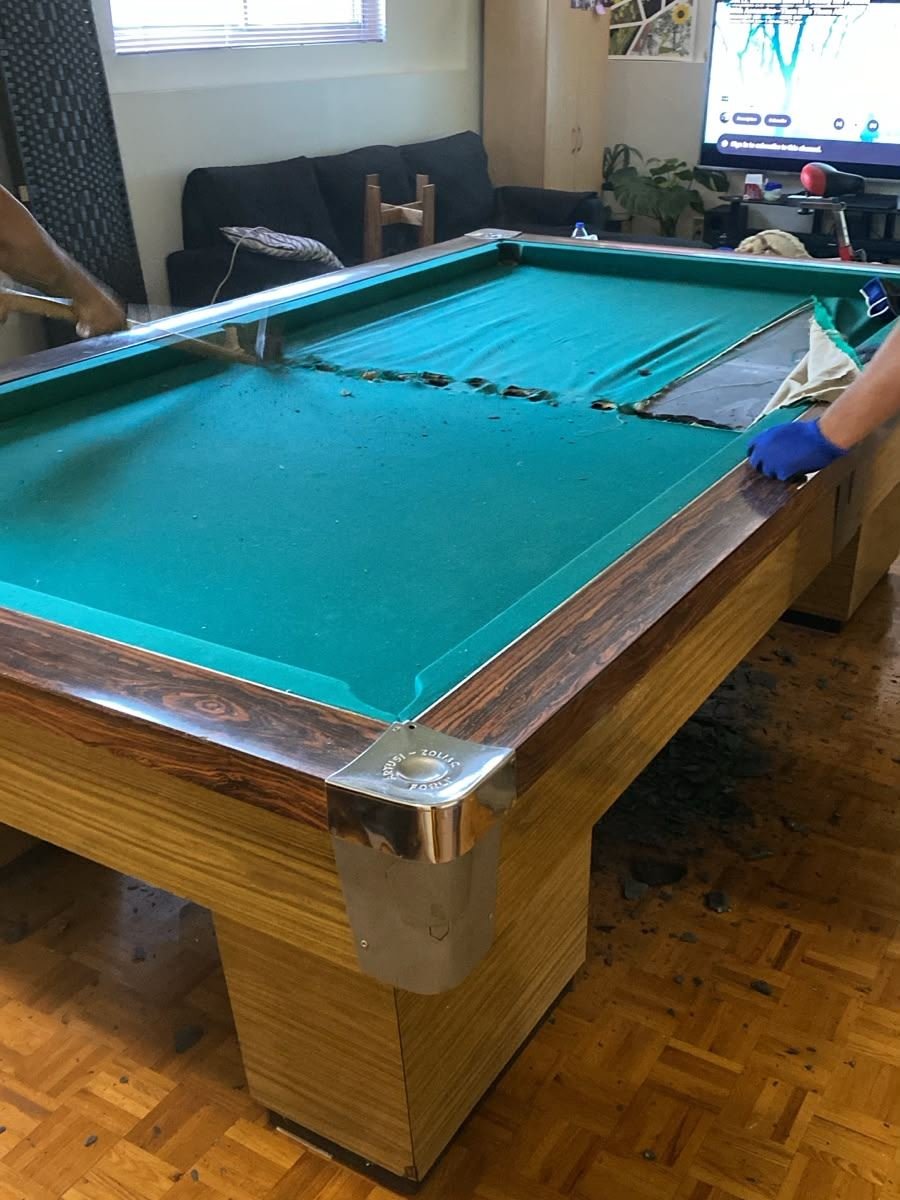 Crew taking the felt and slate off a pool table