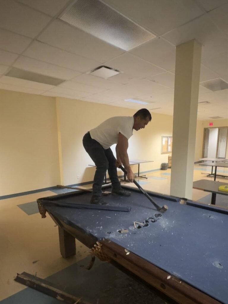 Crew member breaking down a pool table in a community room
