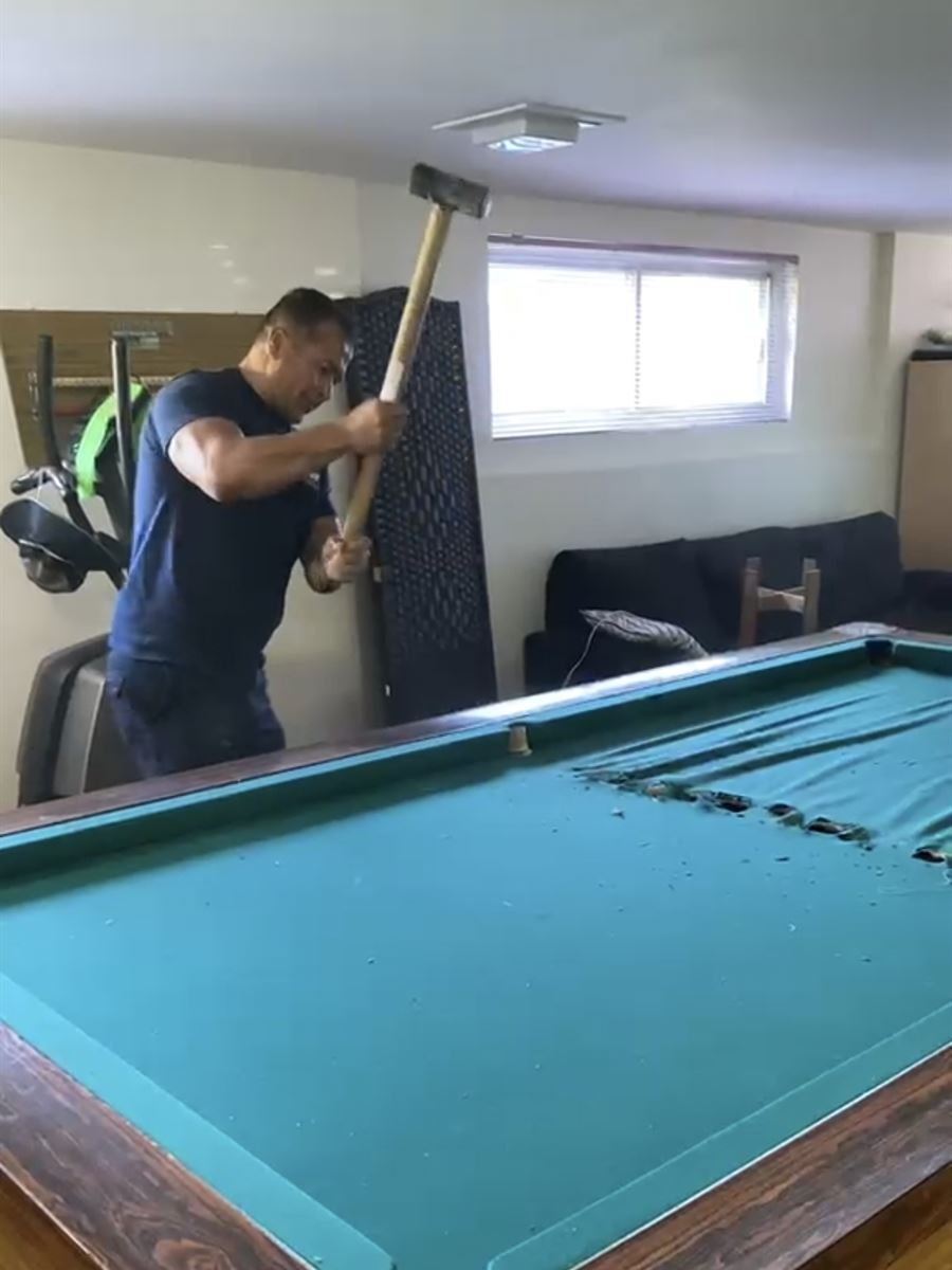 Crew member taking apart a pool table in a basement