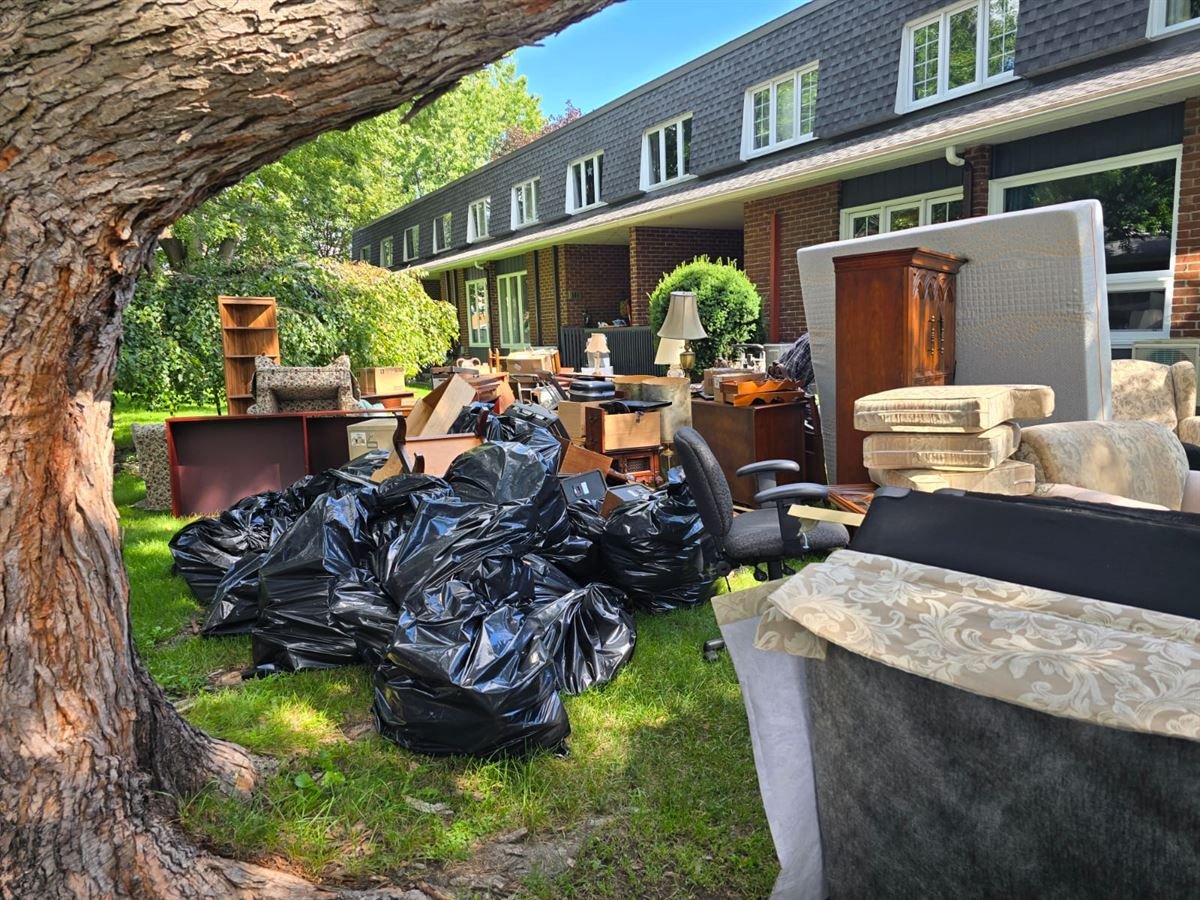 Furniture and bagged items from a downsizing staged on the lawn