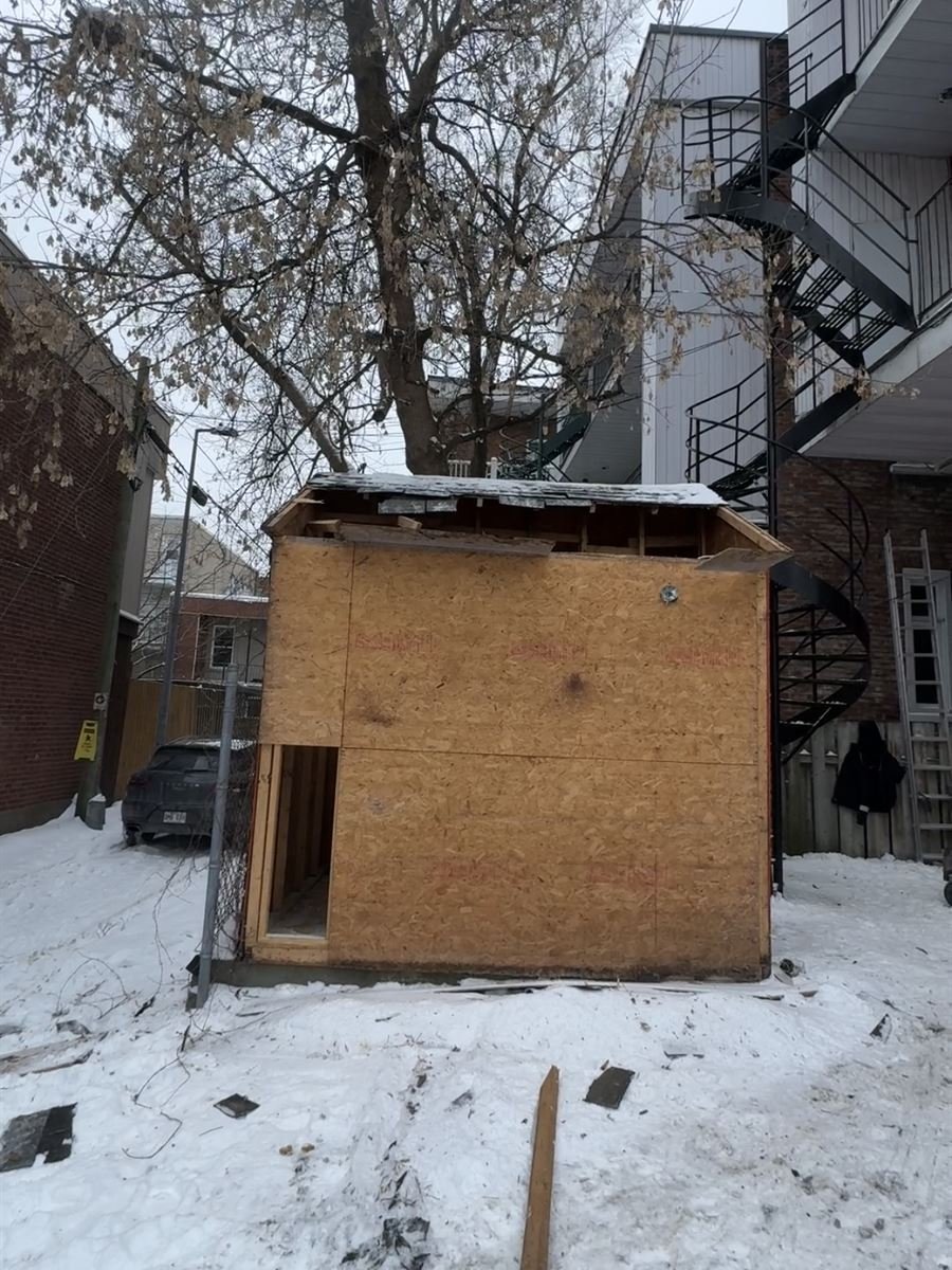 Old plywood shed in a snowy backyard before removal