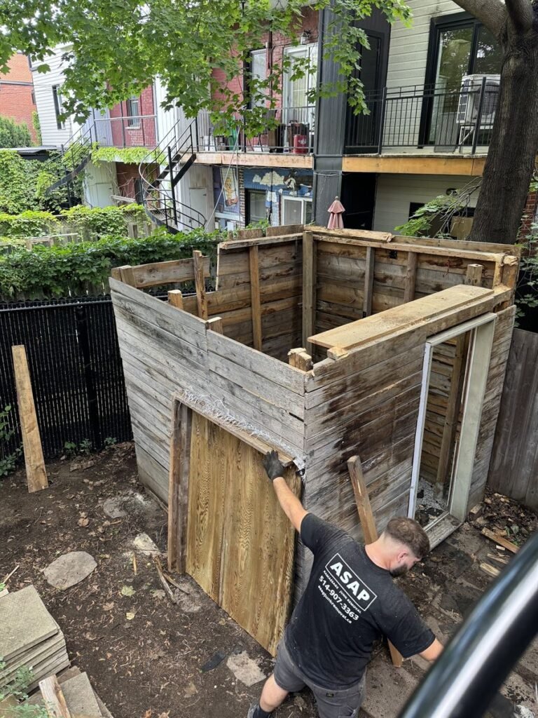 ASAP crew member taking down the walls of a wooden shed