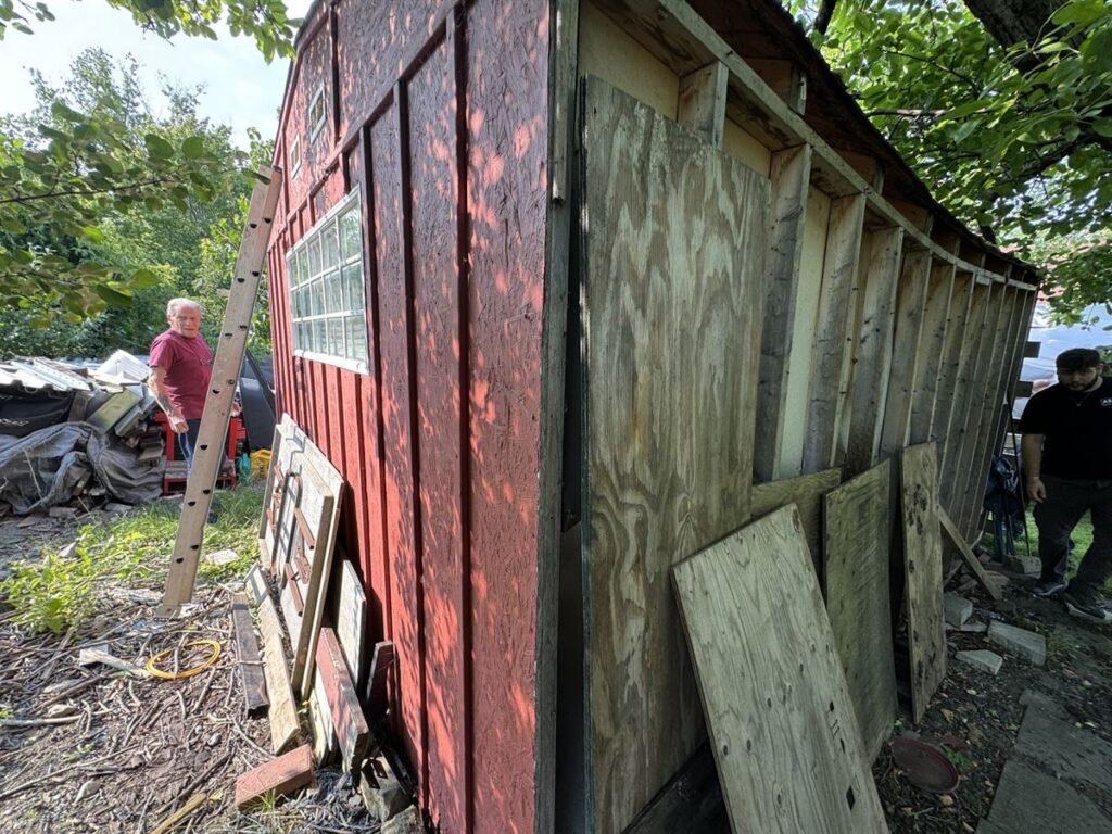 Crew working around a weathered shed being taken apart