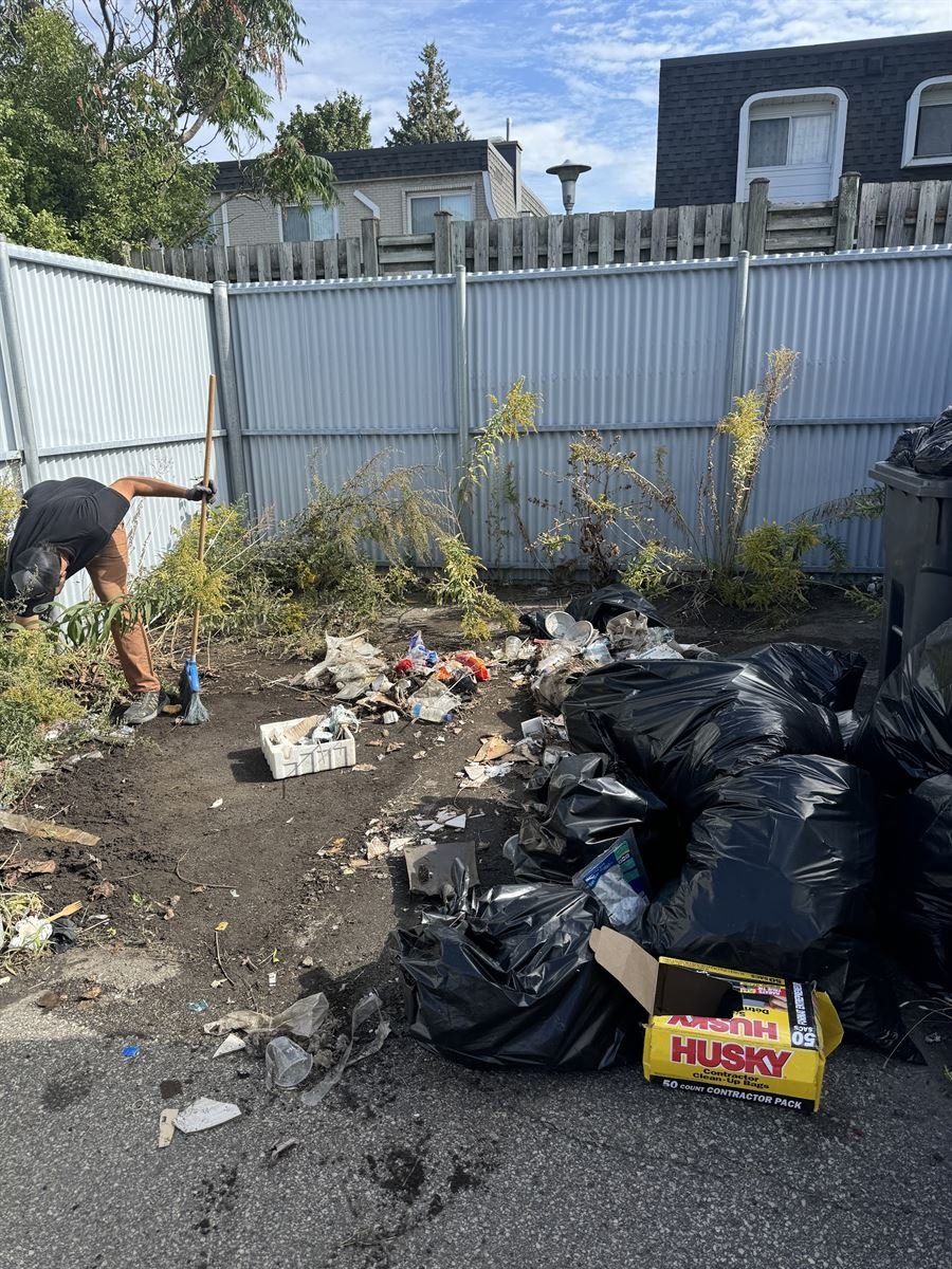 ASAP crew member clearing weeds and bagged yard waste